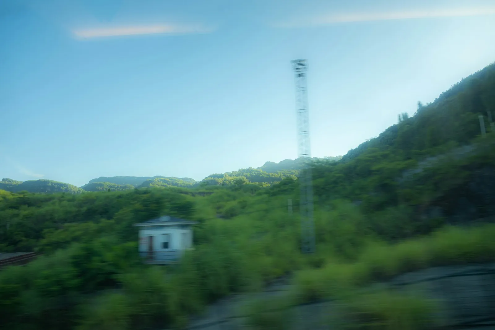 Countryside seen from a train window, illustrating the journey between two cities.