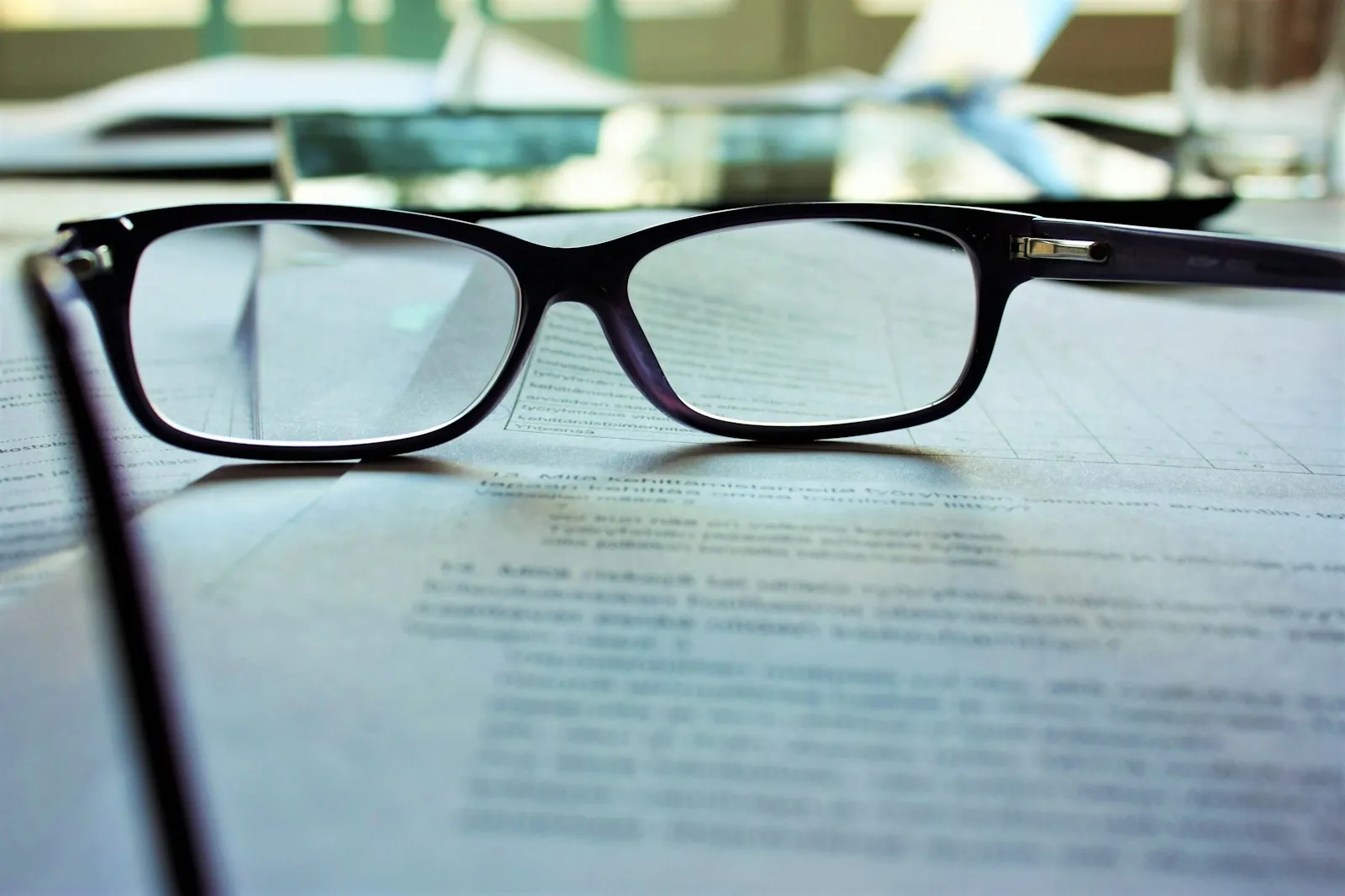 A policy document and reading glasses, illustrating checking insurance before travelling.