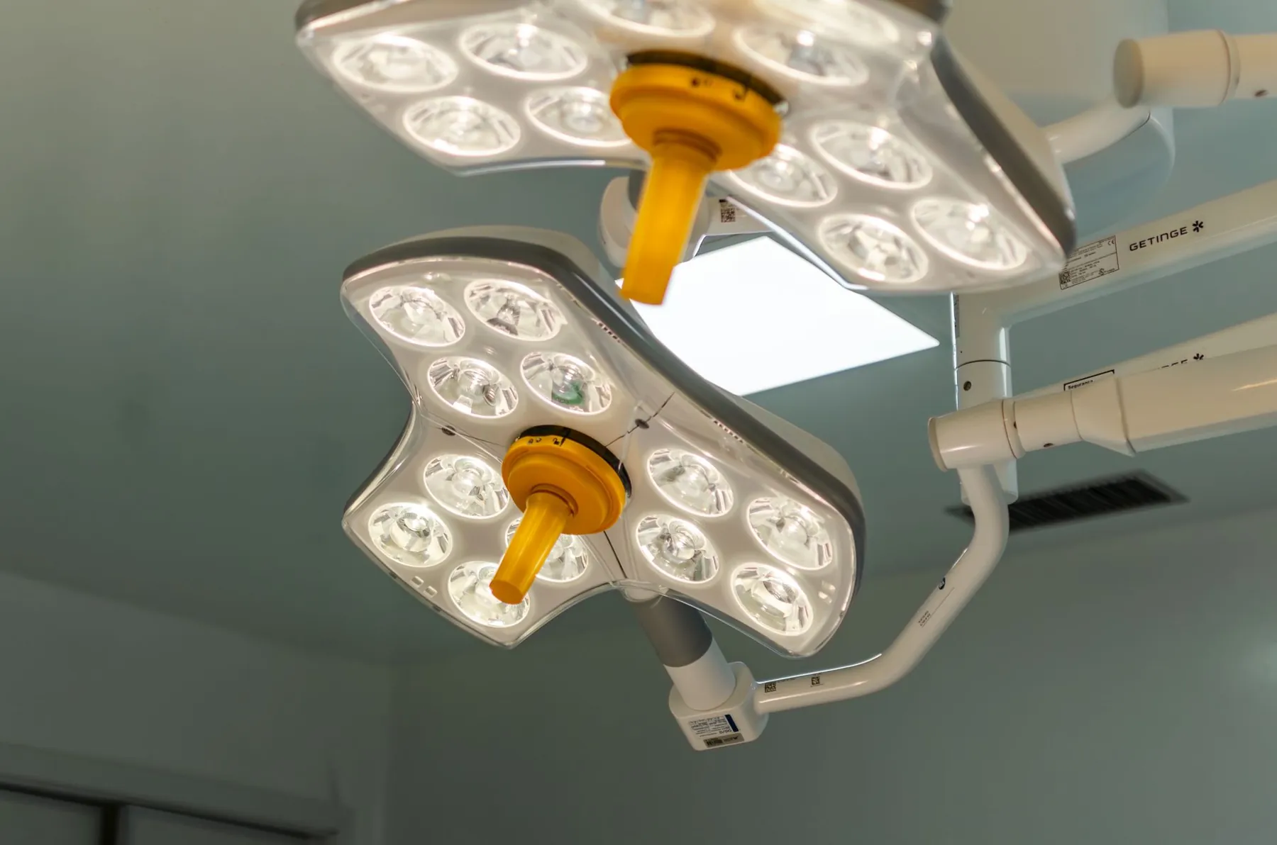 Operating theatre lights above an empty table, illustrating where a facelift is performed.