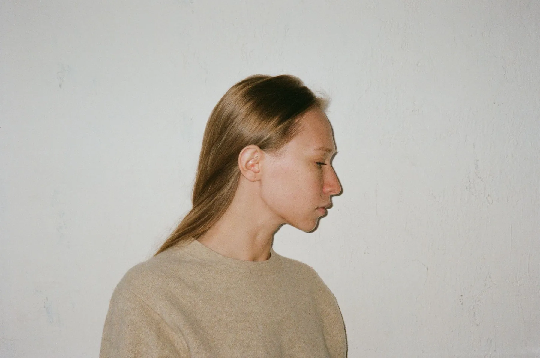 A calm side profile against a plain wall in soft daylight. An illustrative photograph: not a patient of this practice, and not a depiction of results.