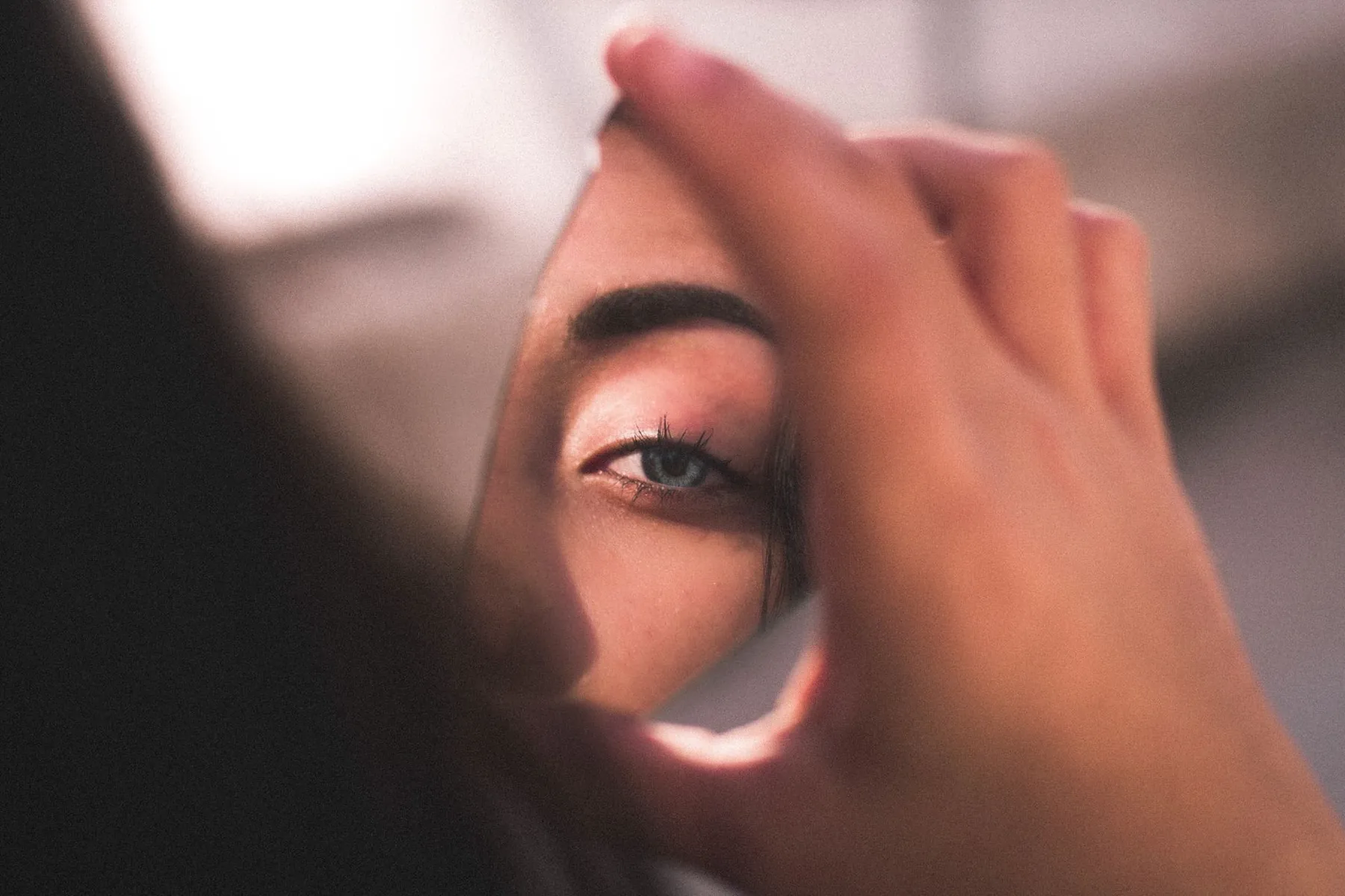 A reflection in a mirror, illustrating assessing your own eyelids before a consultation.